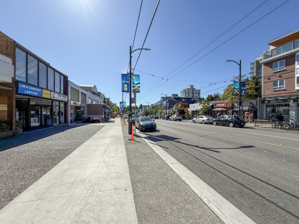 Sidewalk view along West 41st Avenue through the Kerrisdale Village shops, with a KERRISDALE street banner on the pole overhead, in Kerrisdale, Vancouver