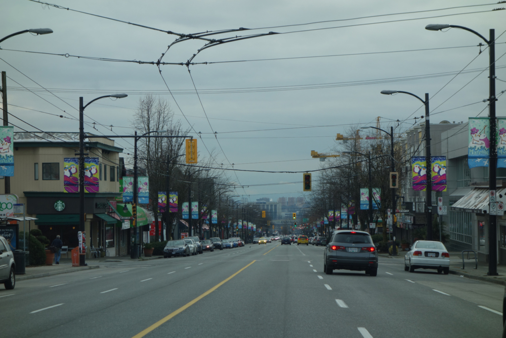 Marpole, Vancouver Granville Street looking north from West 64th Avenue, with trolley wires, street trees and low-rise shopfronts in Marpole, Vancouver